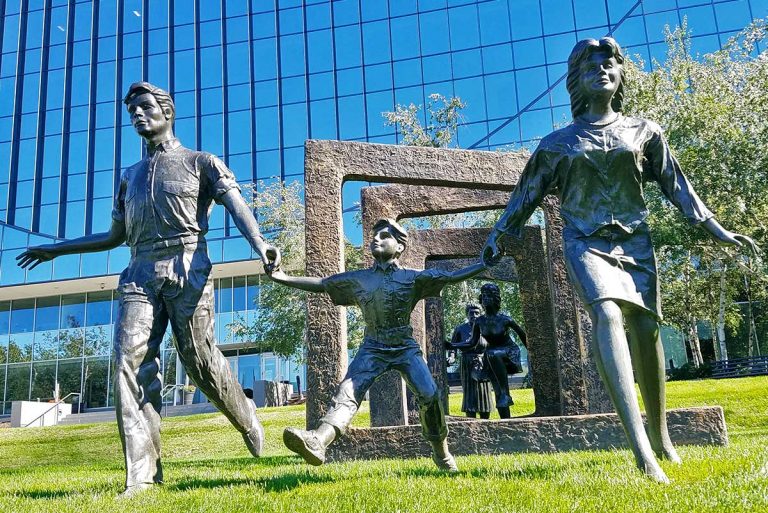 Statue of family skipping through grass field